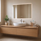 Bathroom vanity with a sink, rectangular LED mirror, and toiletries against a tiled wall.
