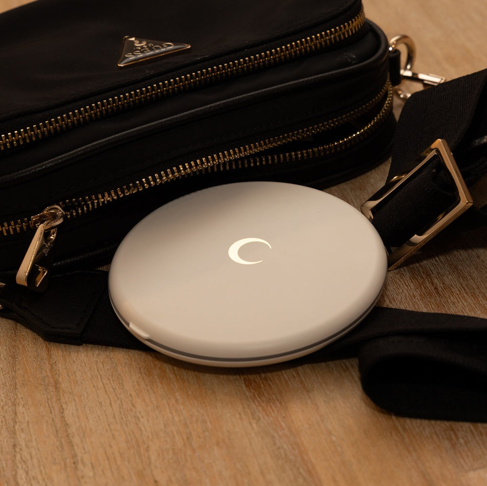 Black handbag with a white round device on a wooden surface