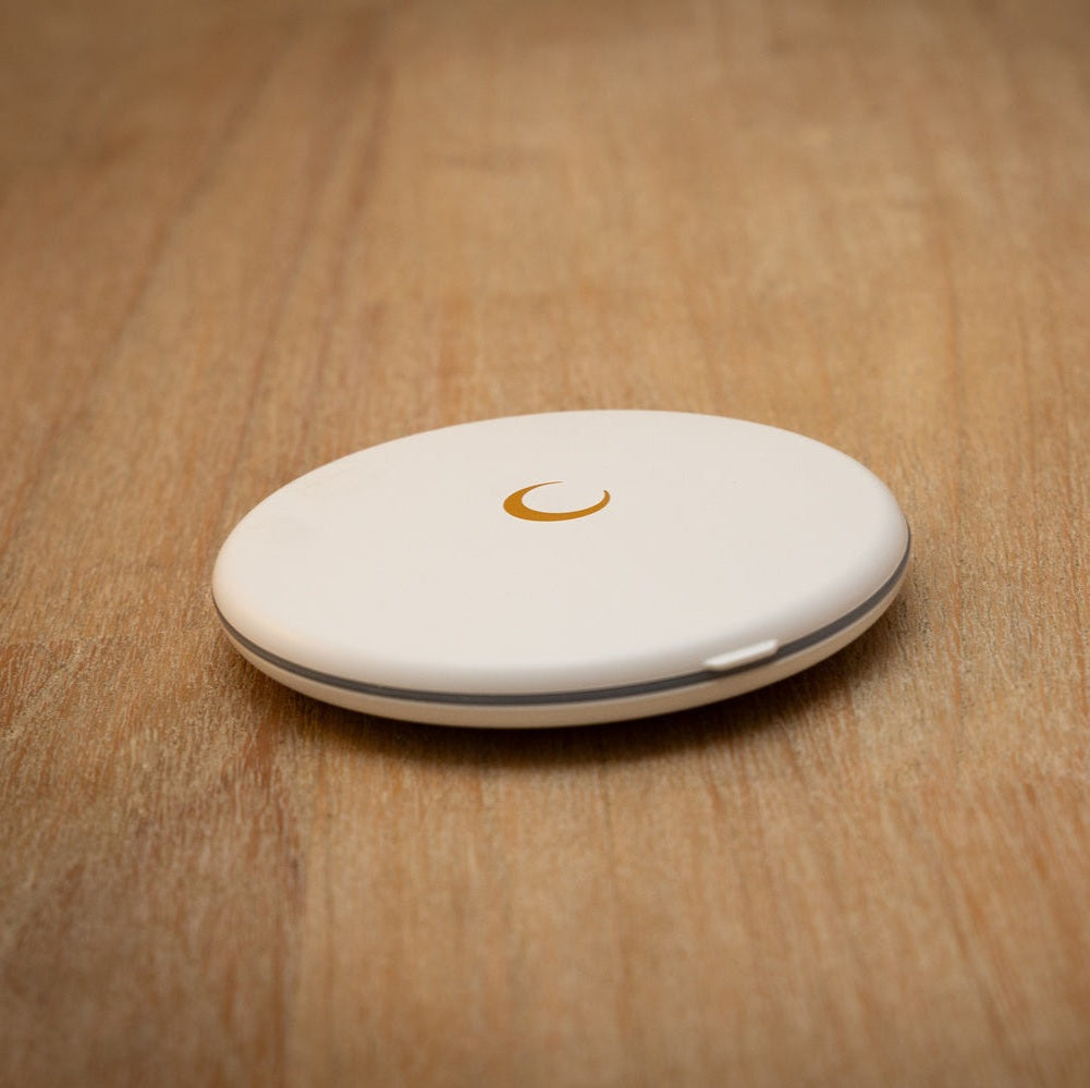 White round LED compact mirror with golden moon emblem on a wooden table.