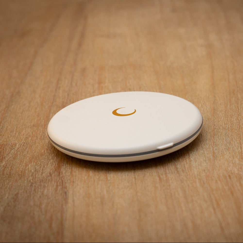 White round LED compact mirror with golden moon emblem on a wooden table.