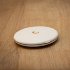 White round LED compact mirror with golden moon emblem on a wooden table.