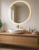 Bathroom vanity with round LED mirror, sink, and wooden cabinet.